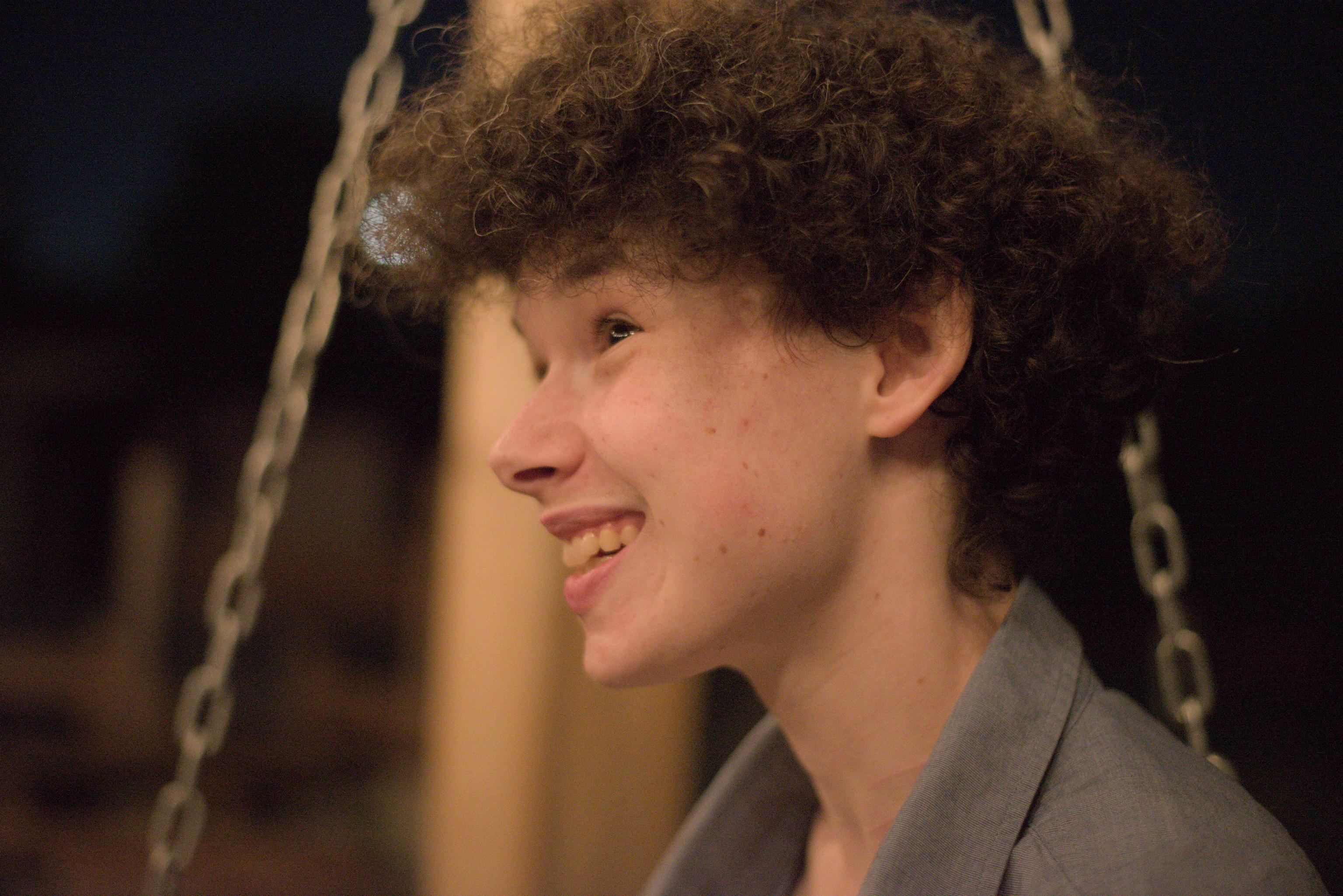 Face and shoulders of white person with curly brown hair and brown eyes